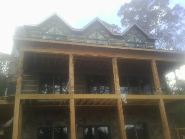 Dormers and porch framing on a large log home under construction — Roof Coating work by our crew in Piney Creek