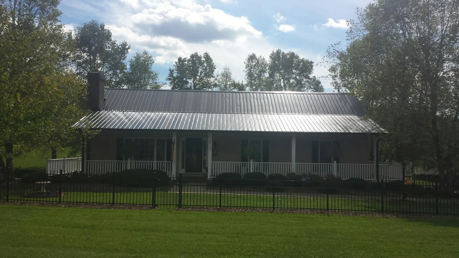 Gray metal roof on a brick ranch with a full width front porch — Gutter Guard Installation work by our crew in Piney Creek