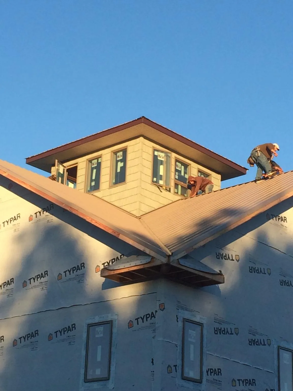 Roofers working around a rooftop cupola on a new metal roof at sunset — Roof Waterproofing in Piney Creek by Roofing Brothers